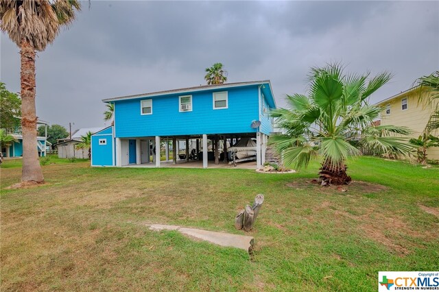 back of property with a lawn and a carport