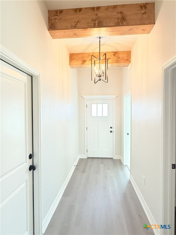 unfurnished living room with ceiling fan with notable chandelier, sink, and vaulted ceiling with beams