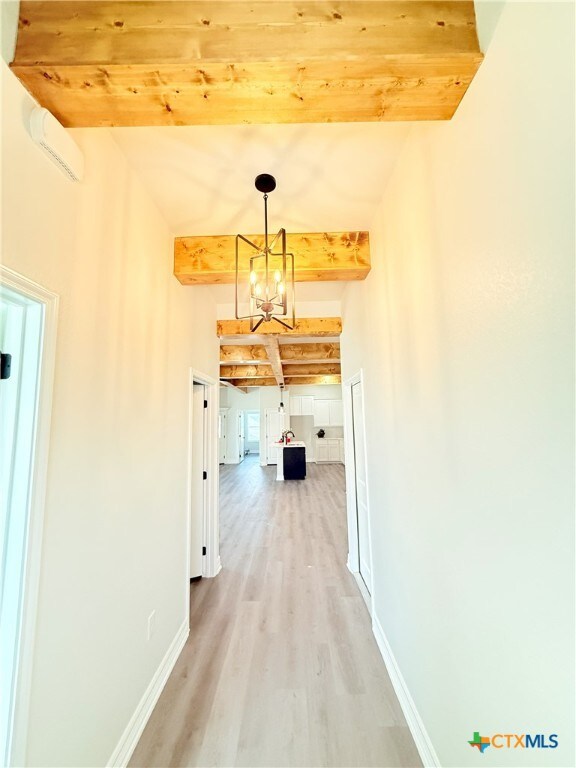 foyer entrance featuring beam ceiling, concrete flooring, and a notable chandelier