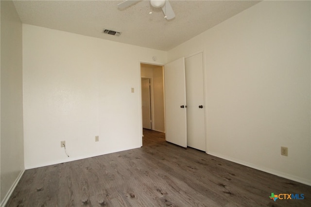 empty room with a textured ceiling, dark hardwood / wood-style floors, and ceiling fan