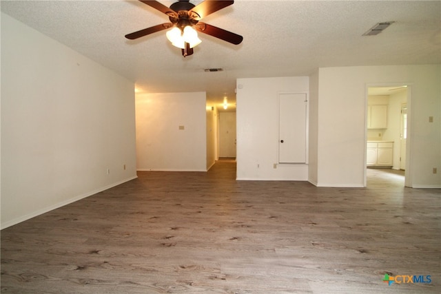 empty room featuring ceiling fan, wood-type flooring, and a textured ceiling