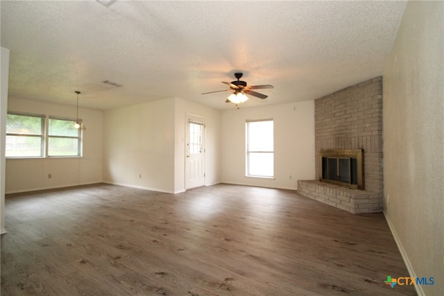 unfurnished living room with a textured ceiling, ceiling fan, dark hardwood / wood-style flooring, and a fireplace