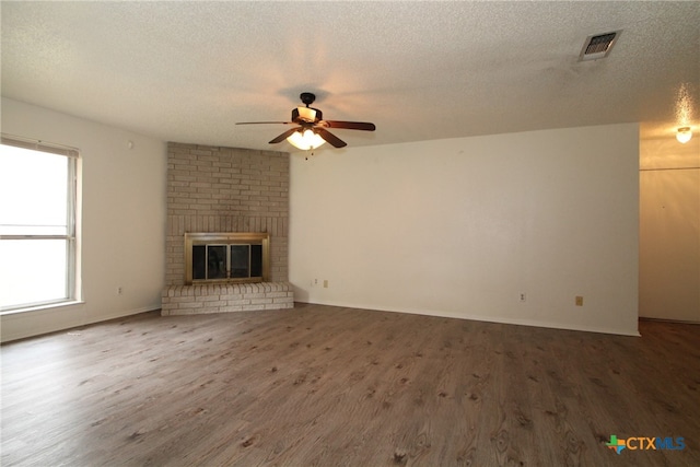 unfurnished living room featuring hardwood / wood-style floors, ceiling fan, a textured ceiling, and a brick fireplace