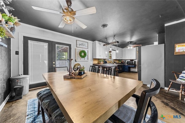 dining area with a ceiling fan and concrete flooring