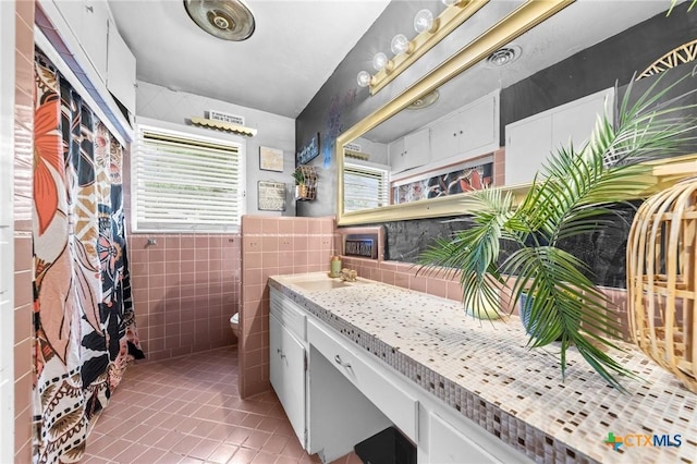 full bathroom featuring tile patterned flooring, tile walls, a wainscoted wall, toilet, and vanity