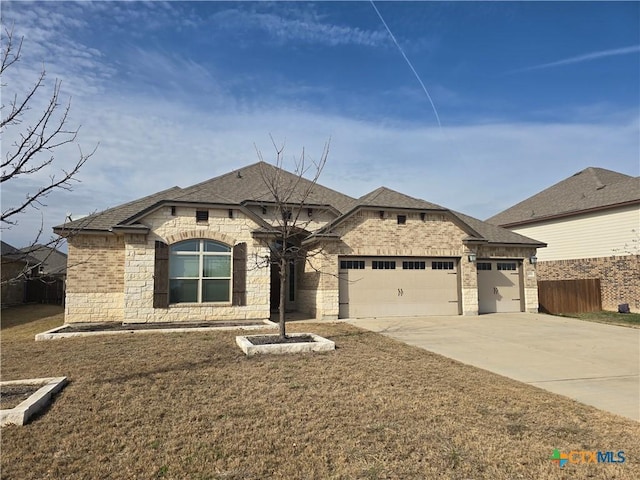 french country home featuring brick siding, concrete driveway, a front yard, fence, and a garage