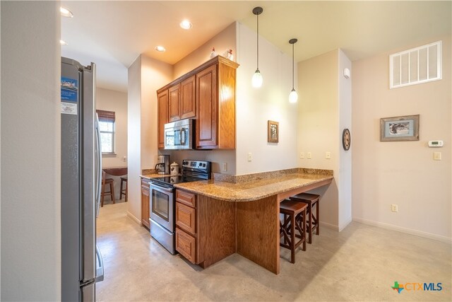 kitchen featuring stainless steel appliances, light stone counters, kitchen peninsula, a kitchen breakfast bar, and decorative light fixtures