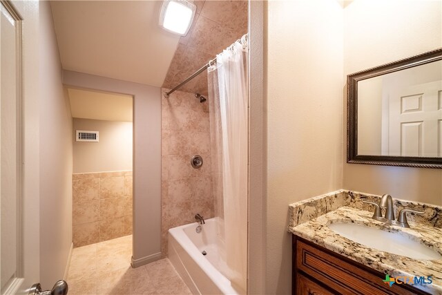 bathroom with shower / bath combination with curtain, vanity, vaulted ceiling, and tile patterned flooring