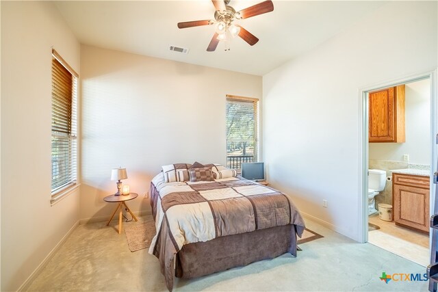 bedroom with ceiling fan, multiple windows, light carpet, and connected bathroom