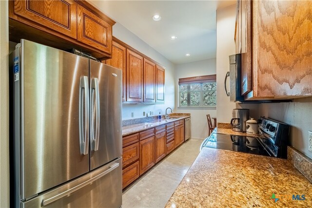 kitchen with sink, light stone counters, and appliances with stainless steel finishes