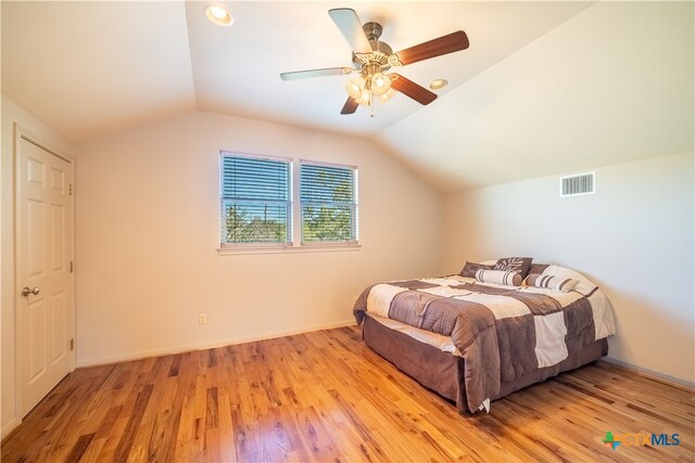 bedroom featuring ceiling fan, light wood-type flooring, and vaulted ceiling