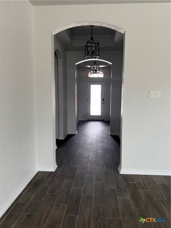 806 Dred Roger Cir, Killeen, TX 76542 - hall featuring arched walkways, dark wood-style flooring, a chandelier, and a tray ceiling