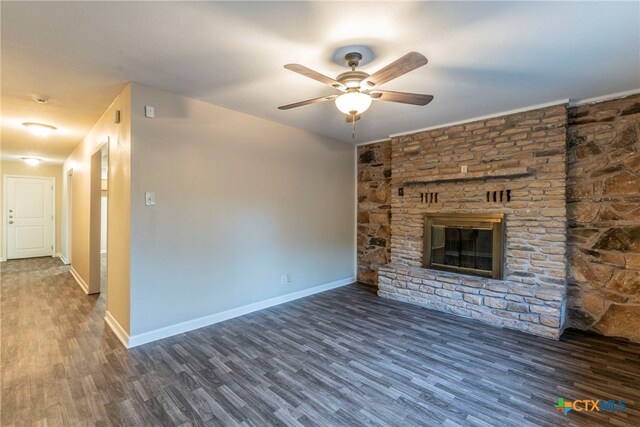 unfurnished living room with a stone fireplace, dark hardwood / wood-style flooring, and ceiling fan