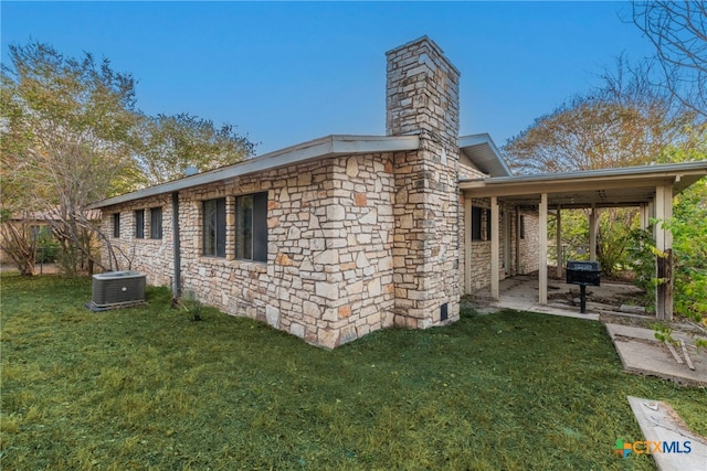 rear view of property featuring central air condition unit and a lawn