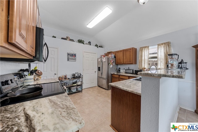 kitchen with lofted ceiling, light stone counters, kitchen peninsula, black appliances, and a breakfast bar area