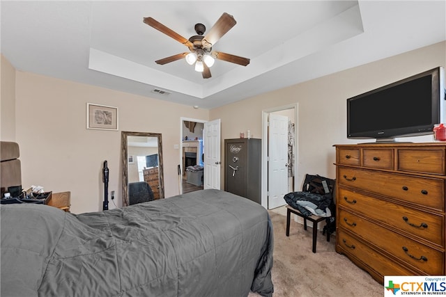 carpeted bedroom with ceiling fan and a raised ceiling