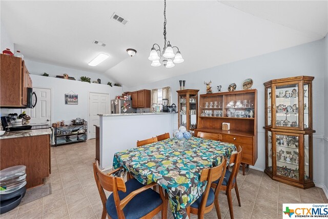 dining space featuring lofted ceiling, a notable chandelier, and light tile patterned flooring