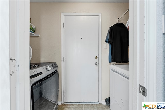 washroom with washing machine and clothes dryer and light tile patterned floors