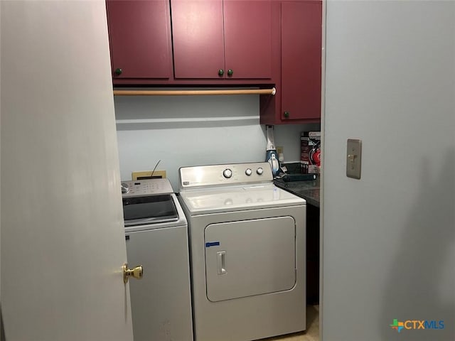 laundry room featuring washer and clothes dryer and cabinets