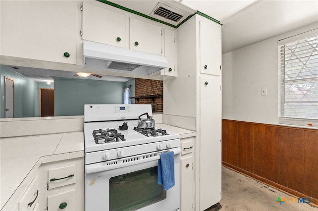 405 Carothers St, Copperas Cove, TX 76522 - kitchen featuring gas range gas stove, under cabinet range hood, white cabinetry, a wainscoted wall, and wood walls