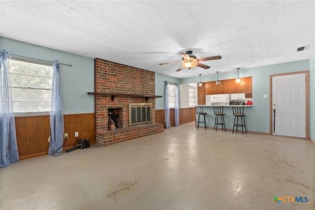 405 Carothers St, Copperas Cove, TX 76522 - unfurnished living room with wooden walls, ceiling fan, concrete flooring, a textured ceiling, and a wainscoted wall