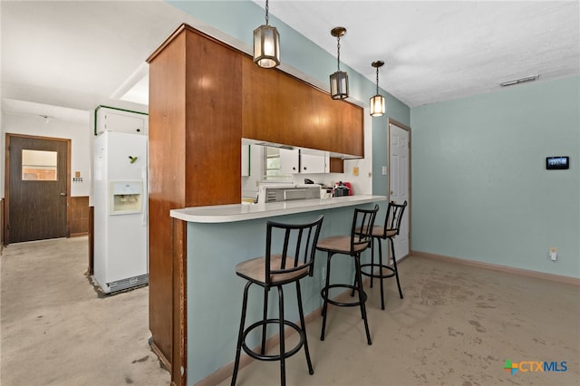 405 Carothers St, Copperas Cove, TX 76522 - kitchen featuring white fridge with ice dispenser, concrete flooring, brown cabinetry, hanging light fixtures, and a breakfast bar area