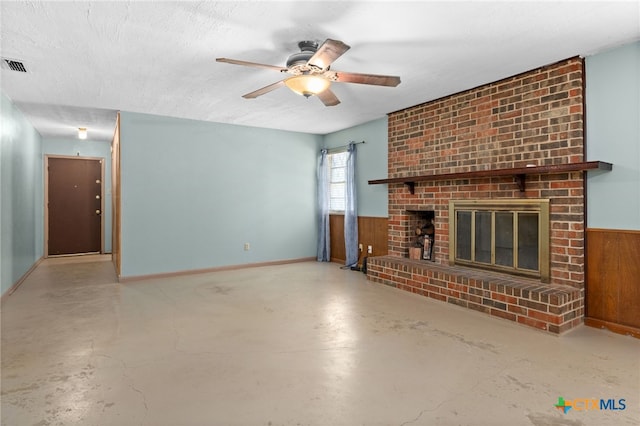 405 Carothers St, Copperas Cove, TX 76522 - unfurnished living room featuring finished concrete floors, ceiling fan, a fireplace, wooden walls, and a wainscoted wall