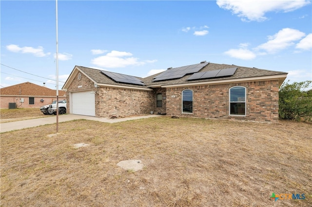 view of front facade with a garage, solar panels, and a front lawn