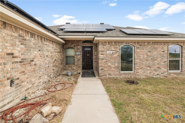 view of exterior entry featuring a lawn and solar panels