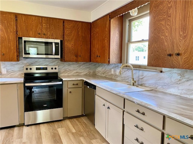 603 E Cedar St, Seguin, TX 78155 - kitchen with appliances with stainless steel finishes, light countertops, light wood-type flooring, backsplash, and brown cabinetry