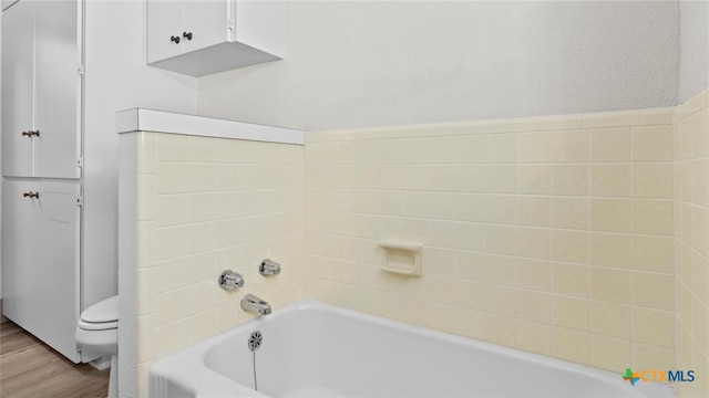 bathroom featuring wood-type flooring, toilet, and a tub