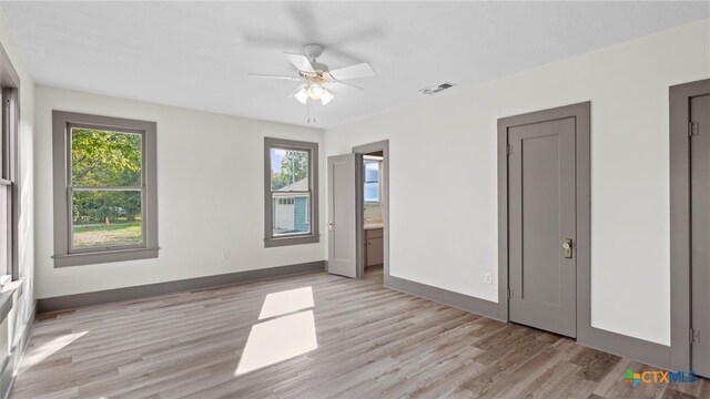 unfurnished bedroom featuring ceiling fan, light wood-type flooring, and multiple windows