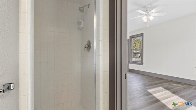 bathroom with a tile shower, hardwood / wood-style flooring, and ceiling fan