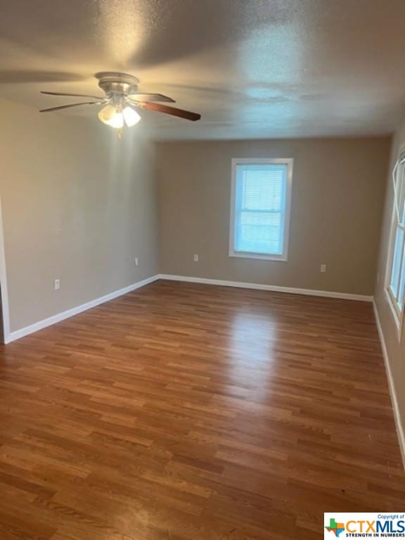 empty room with a textured ceiling, dark hardwood / wood-style flooring, and ceiling fan