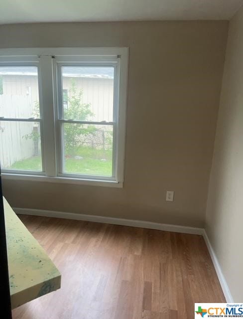 unfurnished room with baseboards and wood finished floors