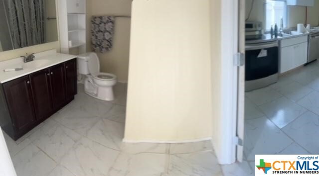 bathroom with toilet, marble finish floor, and vanity