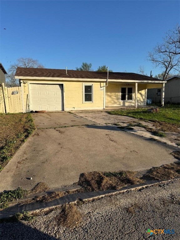 view of front of home with concrete driveway and fence