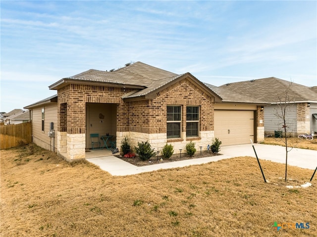 view of front of property featuring brick siding, concrete driveway, an attached garage, fence, and a front lawn