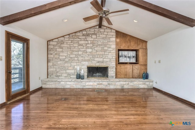 unfurnished living room featuring ceiling fan, a large fireplace, vaulted ceiling with beams, and dark hardwood / wood-style floors