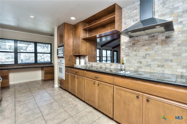 kitchen with electric cooktop, stainless steel microwave, wall chimney range hood, white oven, and backsplash