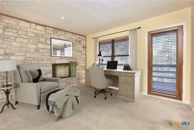 office area with a stone fireplace and light carpet