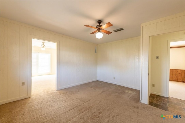 carpeted spare room featuring visible vents and ceiling fan