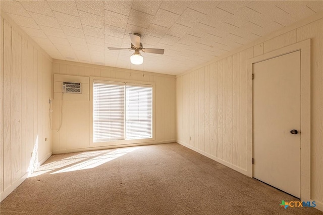 empty room with carpet floors, a wall mounted air conditioner, wood walls, and a ceiling fan