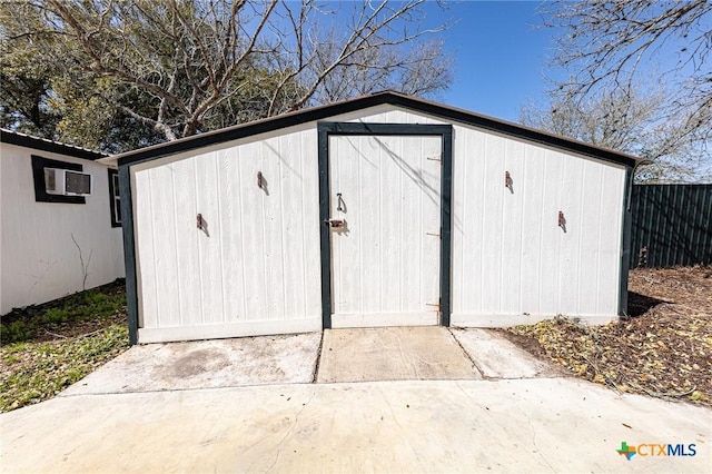 view of shed featuring a wall unit AC and fence