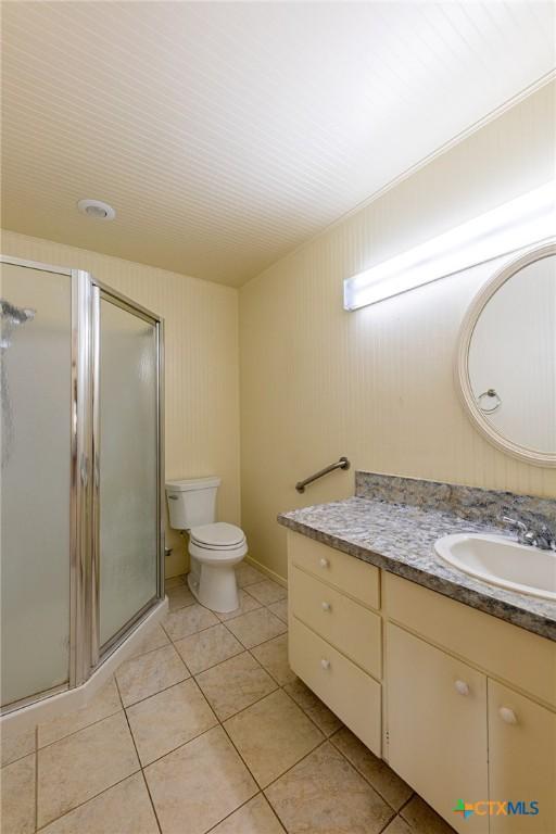 bathroom with toilet, a shower stall, tile patterned flooring, and vanity