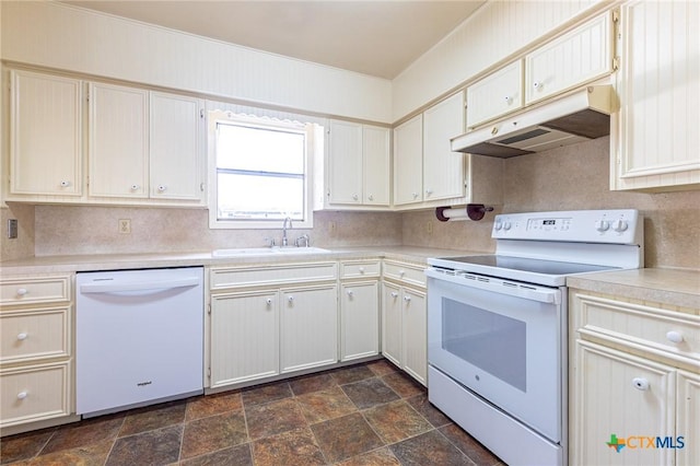 kitchen with white appliances, stone finish floor, light countertops, under cabinet range hood, and a sink