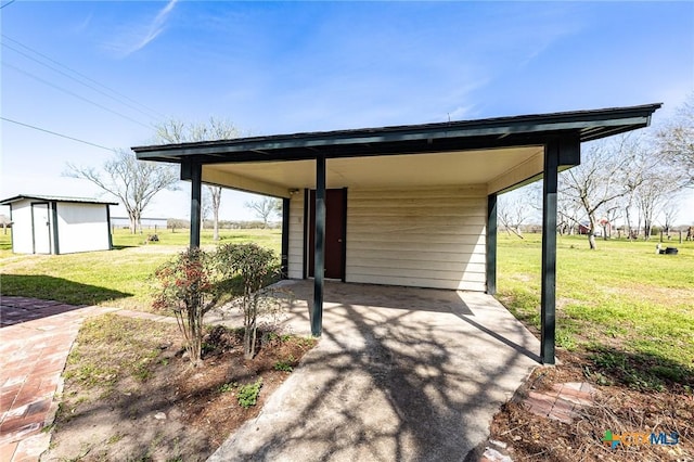 view of patio featuring a carport, an outdoor structure, and driveway