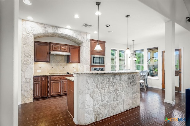2051 Western Pecan, New Braunfels, TX 78130 - kitchen featuring stainless steel microwave, wood tiled floor, a center island, visible vents, and backsplash