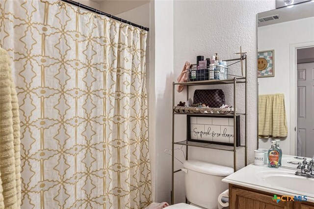 2642 Grayson Way, San Antonio, TX 78232 - bathroom featuring toilet, vanity, a textured wall, and a shower with curtain