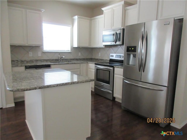 kitchen with dark wood finished floors, a sink, appliances with stainless steel finishes, and tasteful backsplash